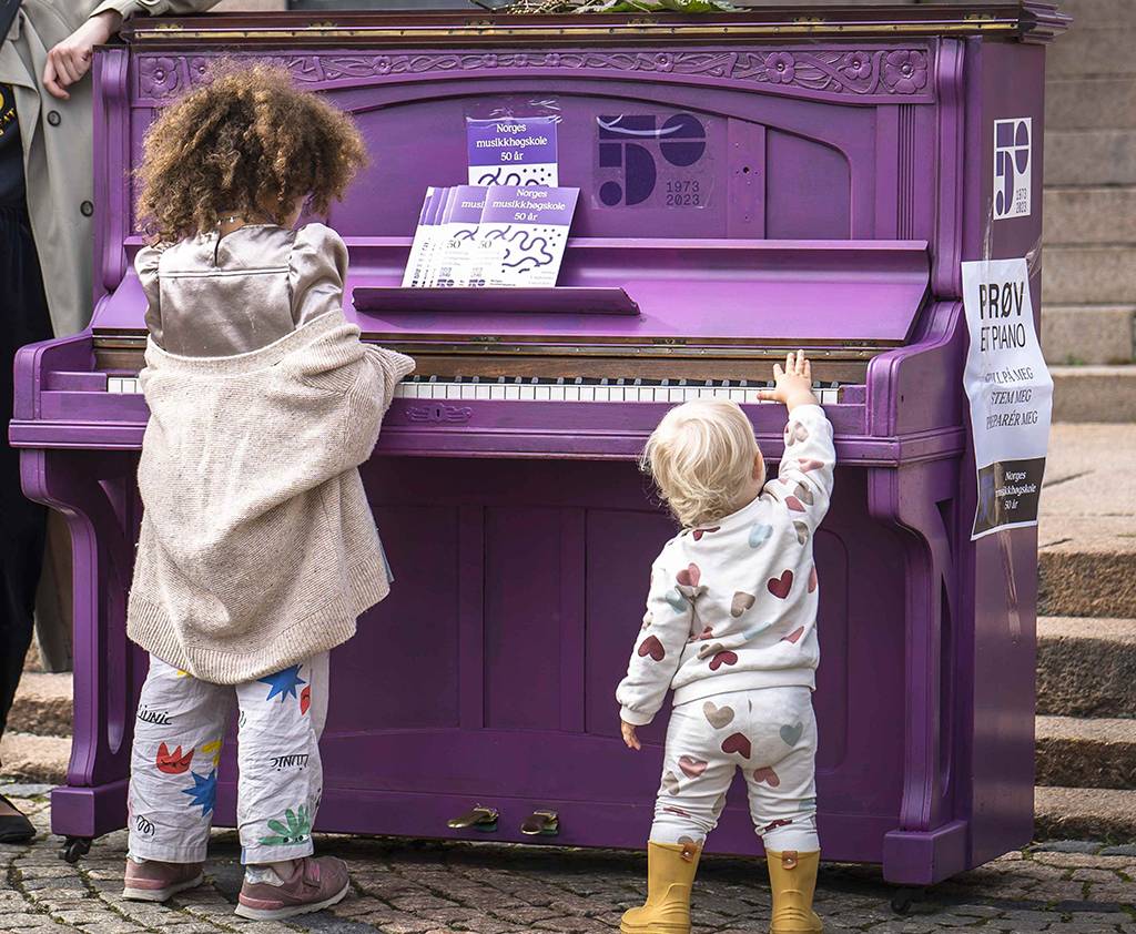 Små barn foran lilla piano