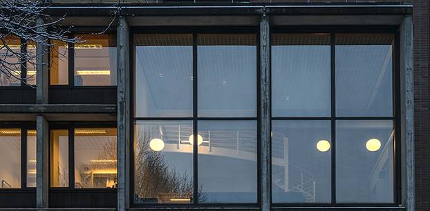 Nærbilde av vindusrutene over inngangen på NMH. Vindeltrappa er synlig på innsiden.